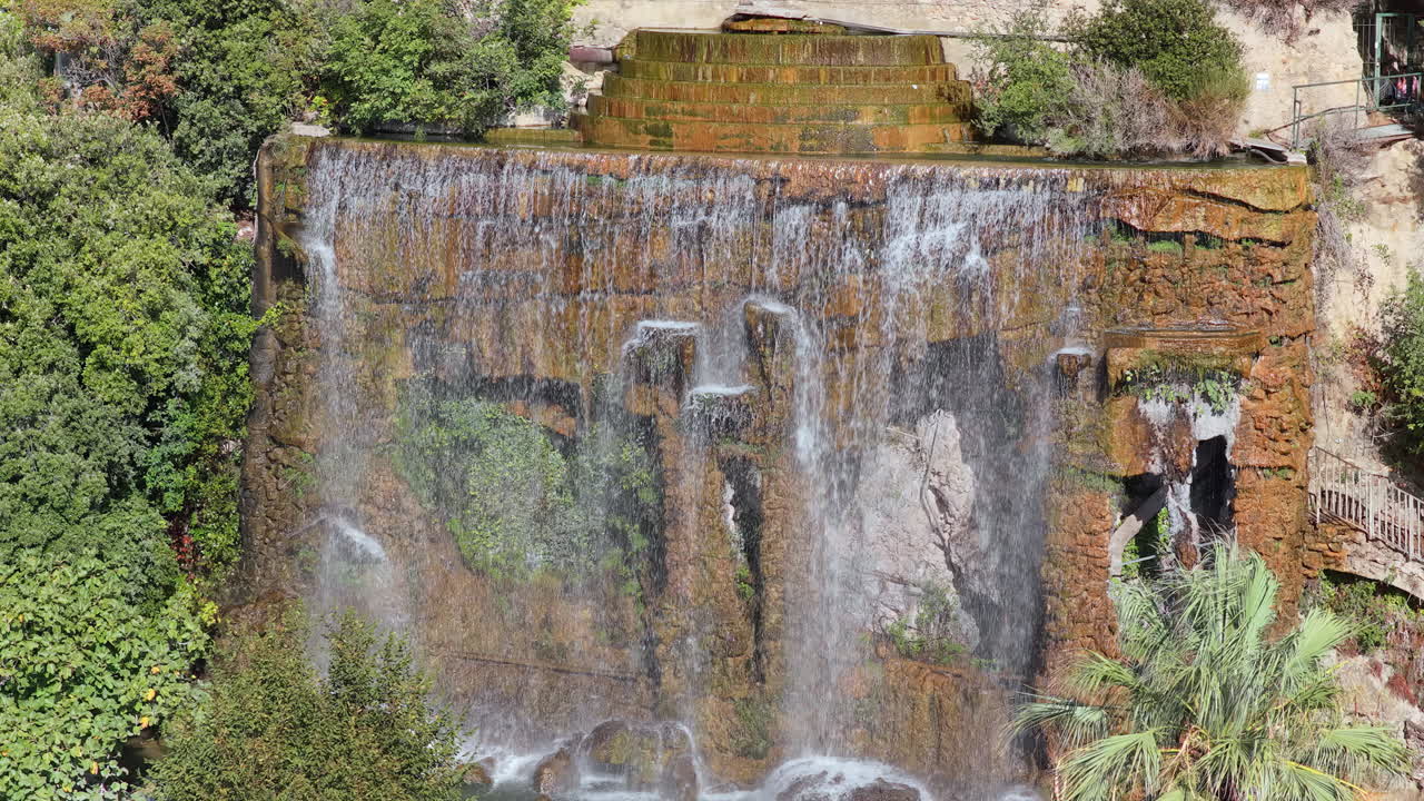 Aerial drone view of the famous waterfall at Castle Hill in Nice, surrounded by lush trees and scenic viewpoints, Nice, France