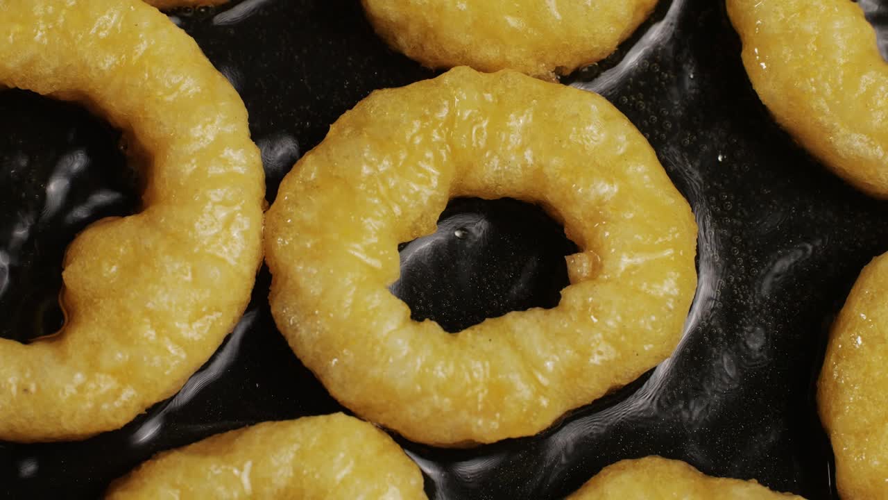 Fried crispy onion rings in a frying pan with boiling oil top view. Roasted onion rings for snacks at bar, cafe. Fast food. Delivery. Beer snacks