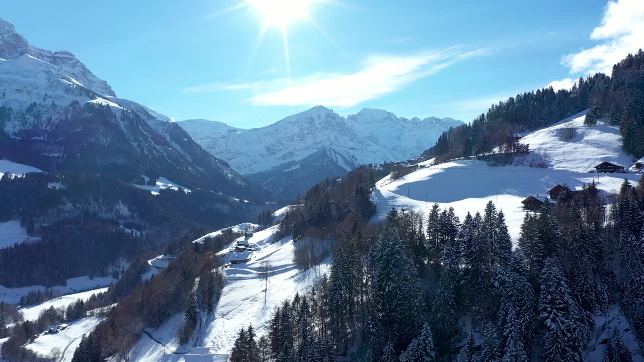 Atemberaubender Drohnenflug über ein beeindruckendes Alpental, Dorf und schneebedeckte Berggipfel in Champéry, Schweiz
