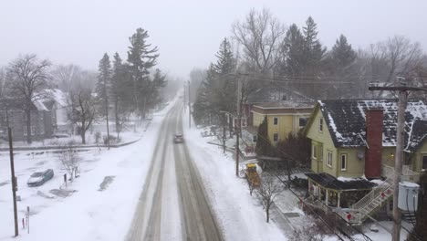 drone dolly over a snowy neighborhood as a snow plow clears sidewalks and cars drive
