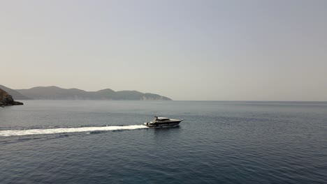 Boat-leaves-the-coast-of-Kefalonia-in-Greece,-beautiful-summer-day,-aerial