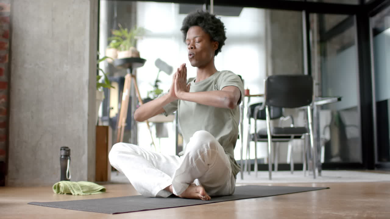 Uomo afroamericano che fa yoga e medita a casa, al rallentatore