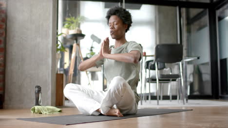 African-american-man-doing-yoga-and-meditating-at-home,-slow-motion