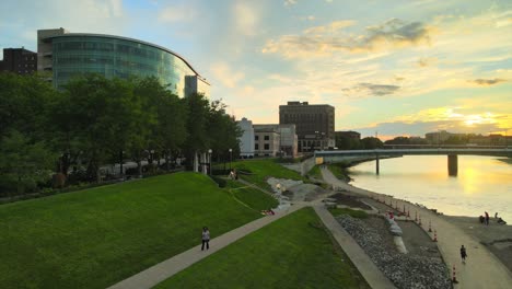 the sun setting while a woman walks along the river.