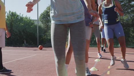 happy diverse female basketball team training with male coach on sunny court, in slow motion