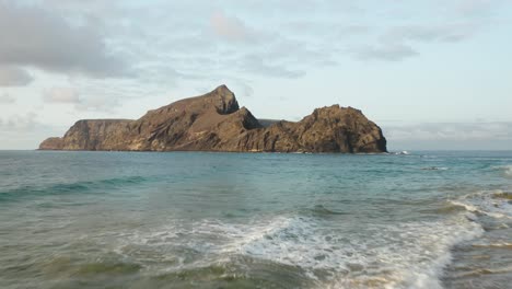 Volando-Hacia-El-Islote-De-Cal-Visto-Desde-La-Playa-De-Ponta-Da-Calheta,-Porto-Santo