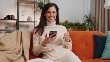 mujer joven feliz en casa usar teléfono inteligente escribir navegación wow sí descubrió gran gran victoria celebrar