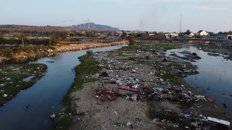 Low-aerial-flying-over-polluted-river-near-Phan-Rang,-Vietnam