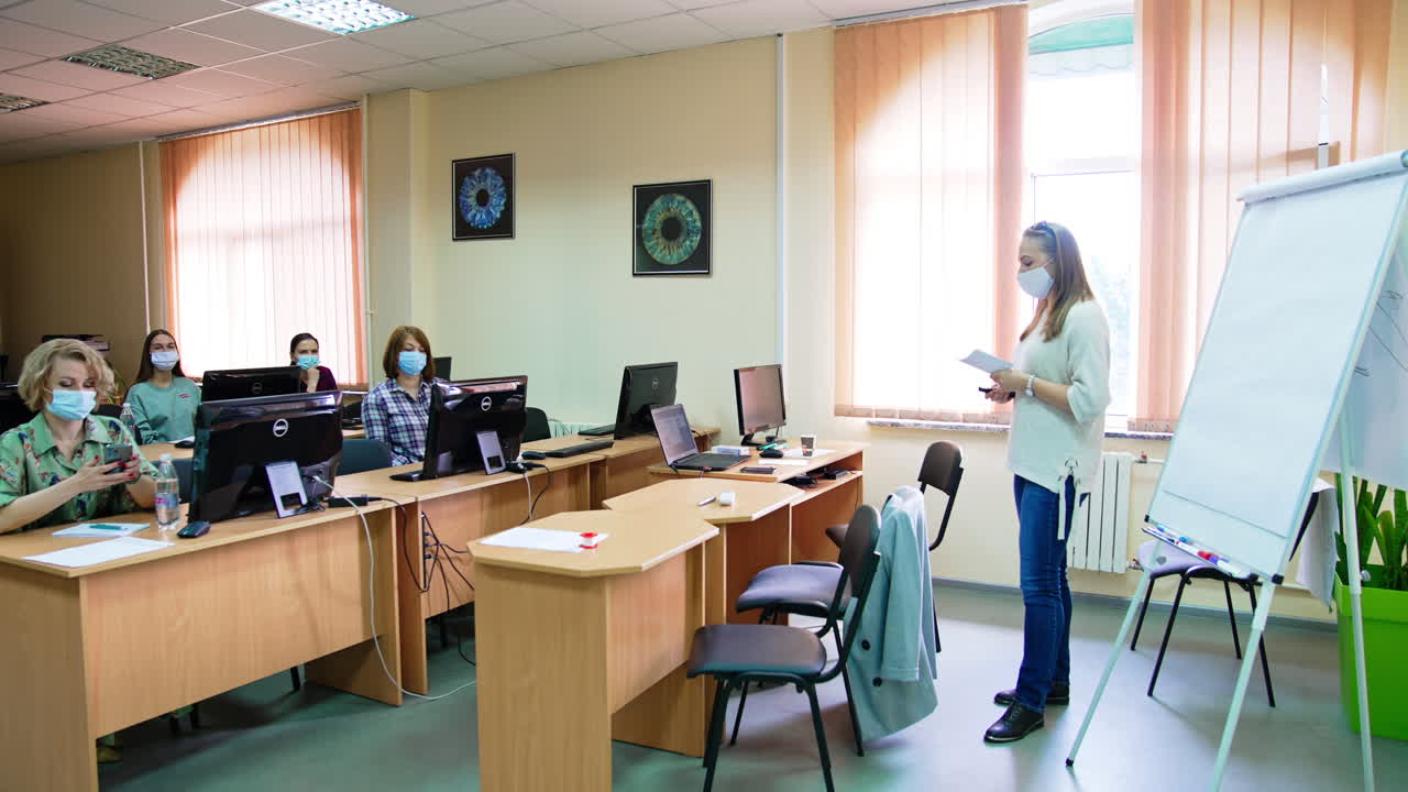 Lecture in medical university. Students sit at computers and the lecturer at the whiteboard reading a course.