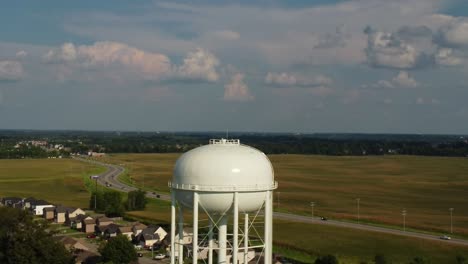 water tower with vehicles driving through fields on a sunny day