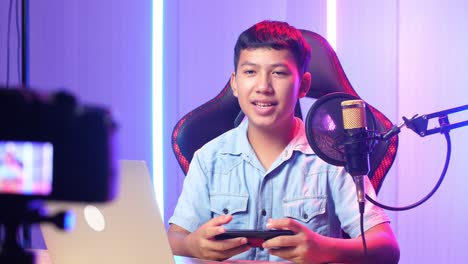 asian kid boy holding mobile phone and talking to camera while live stream