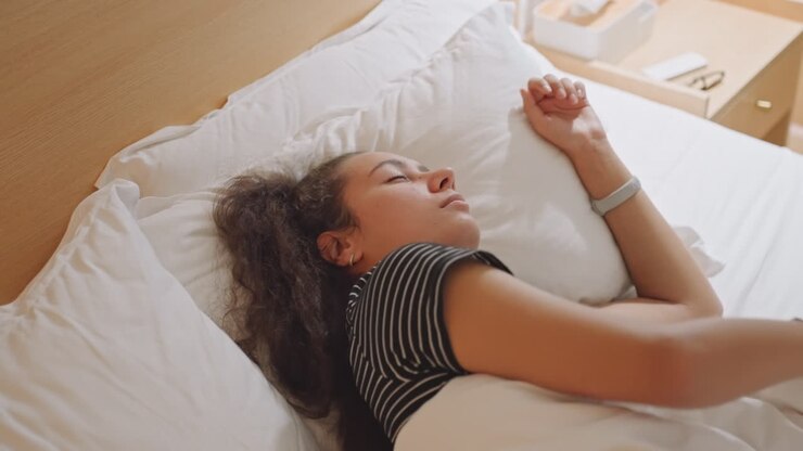 Hotelgæst vågner blidt til blødt sollys, prikket top og hestehale, langsom stræk og dybt åndedræt, sengebord og varm trægavl, stille morgenrutine, diskret smil og afslappet holdning