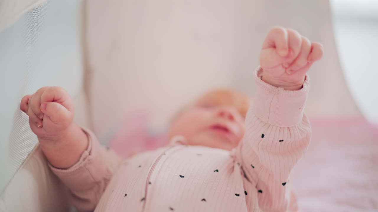 Adorable baby resting in a cozy bed under natural light, wearing pastel pink pajamas