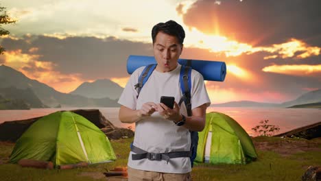 surprised camper checking mobile phone at sunrise
