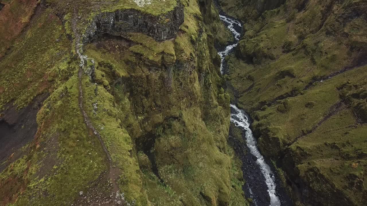 cañón profundo y cascada entre montañas volcánicas en las tierras altas de islandia, antena cinematográfica de drones