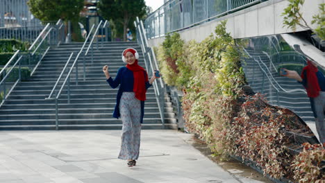 young woman in hijab enjoying music and dancing outdoors in an urban setting