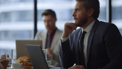 hombre de negocios serio discutiendo el plan de trabajo en una computadora portátil en la oficina del café.