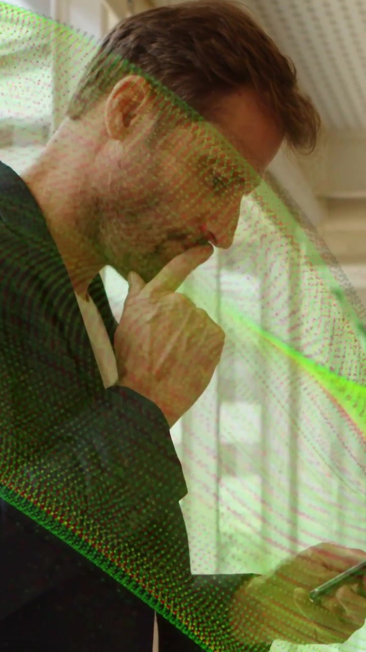 Uomo con blazer scuro che tiene il telefono, legge messaggi, si tocca il mento in carrozza, con sovrapposizione verde.