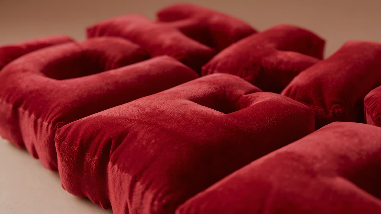 Alejamiento de la cámara y cambio de enfoque para revelar módulos de cojín capitoné de terciopelo rojo sobre una mesa beige