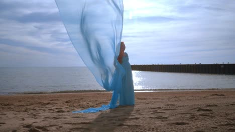 pregnant woman with blue cloth flying on beach. pregnancy concept