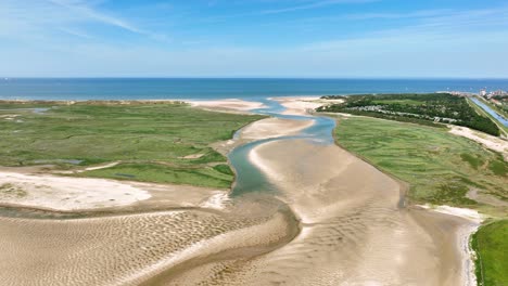 lake and river flowing through green polder landscape at netherlands and belgium border, het zwin nature reserve