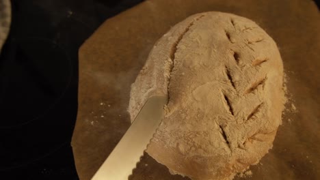 scoring a fresh loaf of homemade sourdough bread