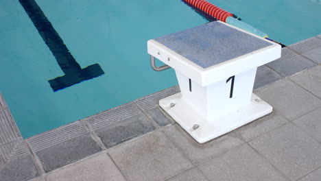 starting block number one stands ready at a swimming pool's edge