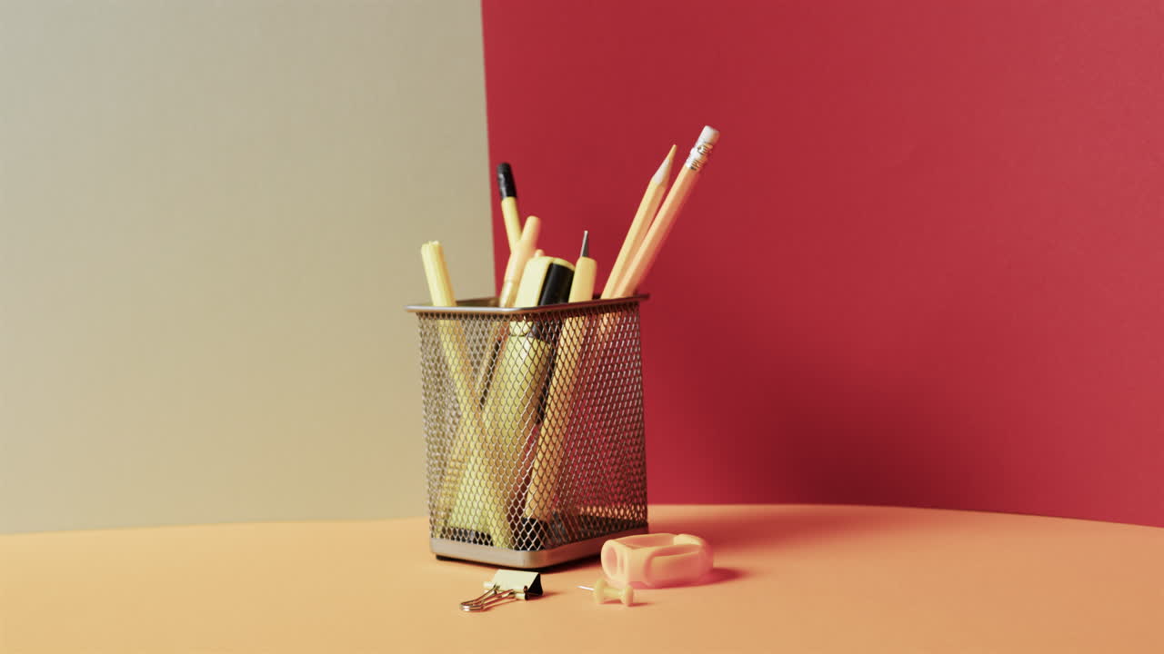 primer plano de papelería escolar en taza con espacio de copia en fondo gris y rojo, en cámara lenta