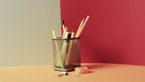 primer plano de papelería escolar en taza con espacio de copia en fondo gris y rojo, en cámara lenta