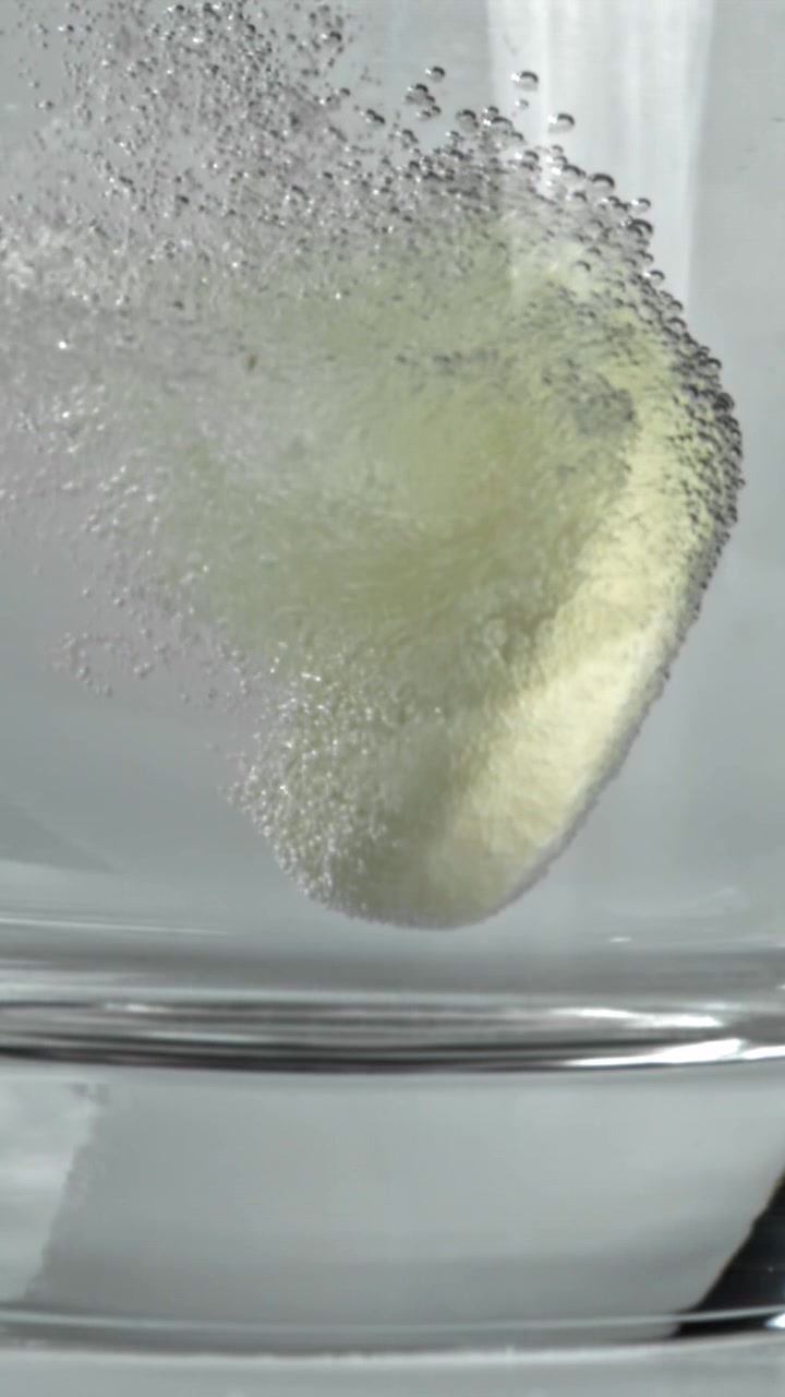 Compressa effervescente che si dissolve e frizzante in un bicchiere d'acqua.