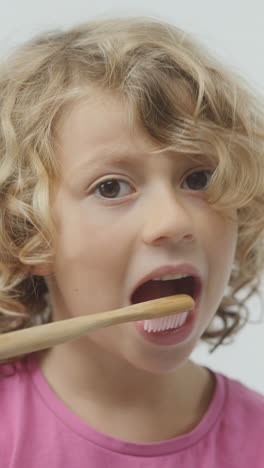 una niña pequeña cepillándose los dientes en vertical