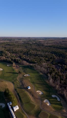 vertical drone overview of tpc toronto osprey valley golf course with wide green fairways and trees, establishing with long shadows