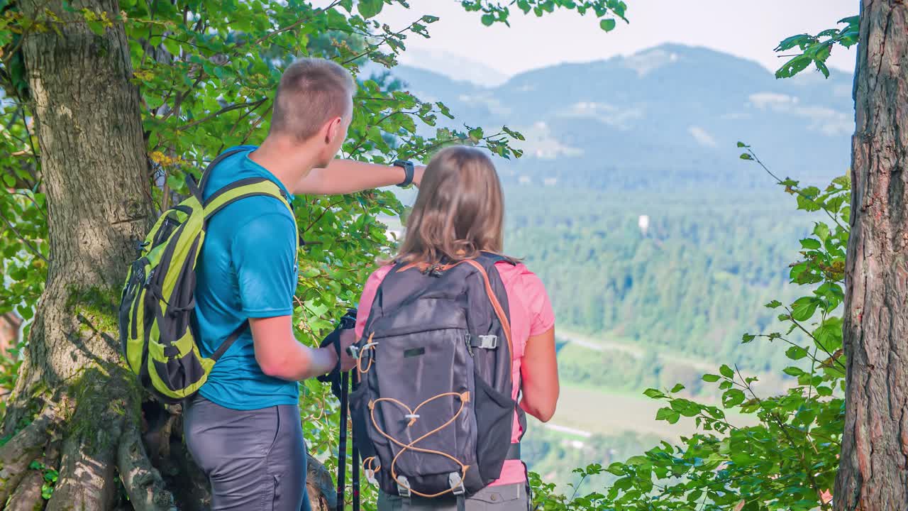 Slow motion of two young travelers appreciating the landscape from a viewpoint on a hill