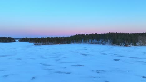 Flying-over-a-frozen-lake-after-sunset-with-magenta-colors