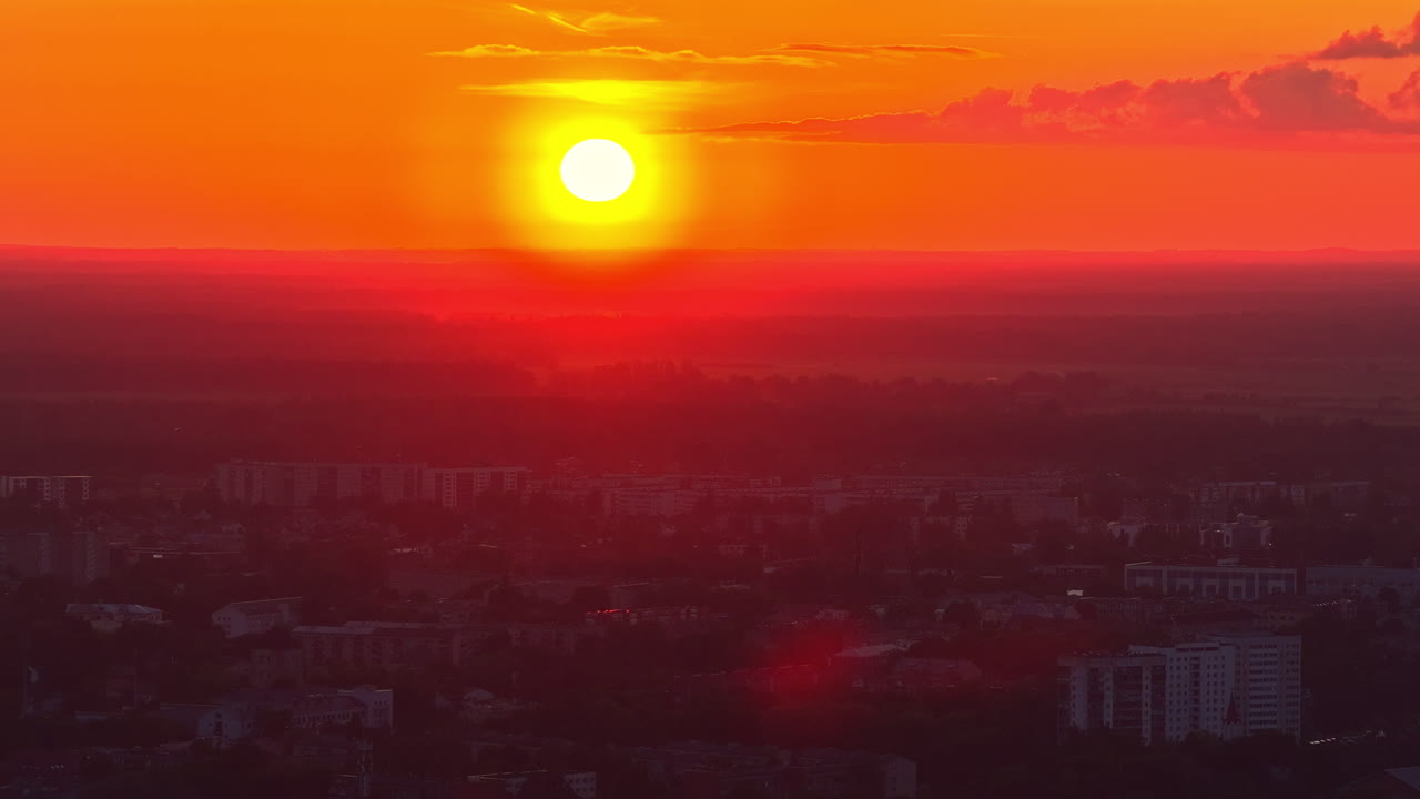 Yellow bright sunset with red sky above city, aerial time lapse view