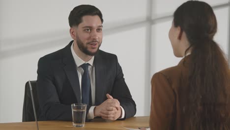 male candidate being interviewed in office for job by female interviewer viewed through window 10