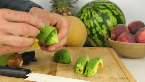 Close-up-of-an-individual-peeling-skins-off-of-avocados