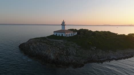 Der-Luftaufstieg-Zeigt-Den-Leuchtturm-Von-Alcanada-Auf-Einer-Felsigen-Insel,-Die-Leuchtend-Weiße-Fassade-Und-Das-Orangefarbene-Dach