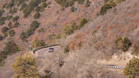 vehicles drive along a winding mountain road, long lens