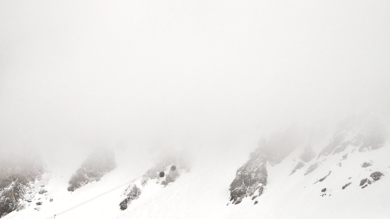 lapso de tiempo de una burbuja de telesilla en la ladera de una montaña que se dirige hacia una nube baja en los alpes franceses en invierno