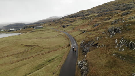 islas feroe, 4k aérea de niðara vatn con dos personas caminando por una carretera