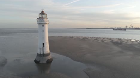 Vista-Aérea-Descendente-Lenta-A-Través-Del-Faro-Británico-Y-Las-Grúas-De-Los-Astilleros-Costeros-Amanecer-Horizonte