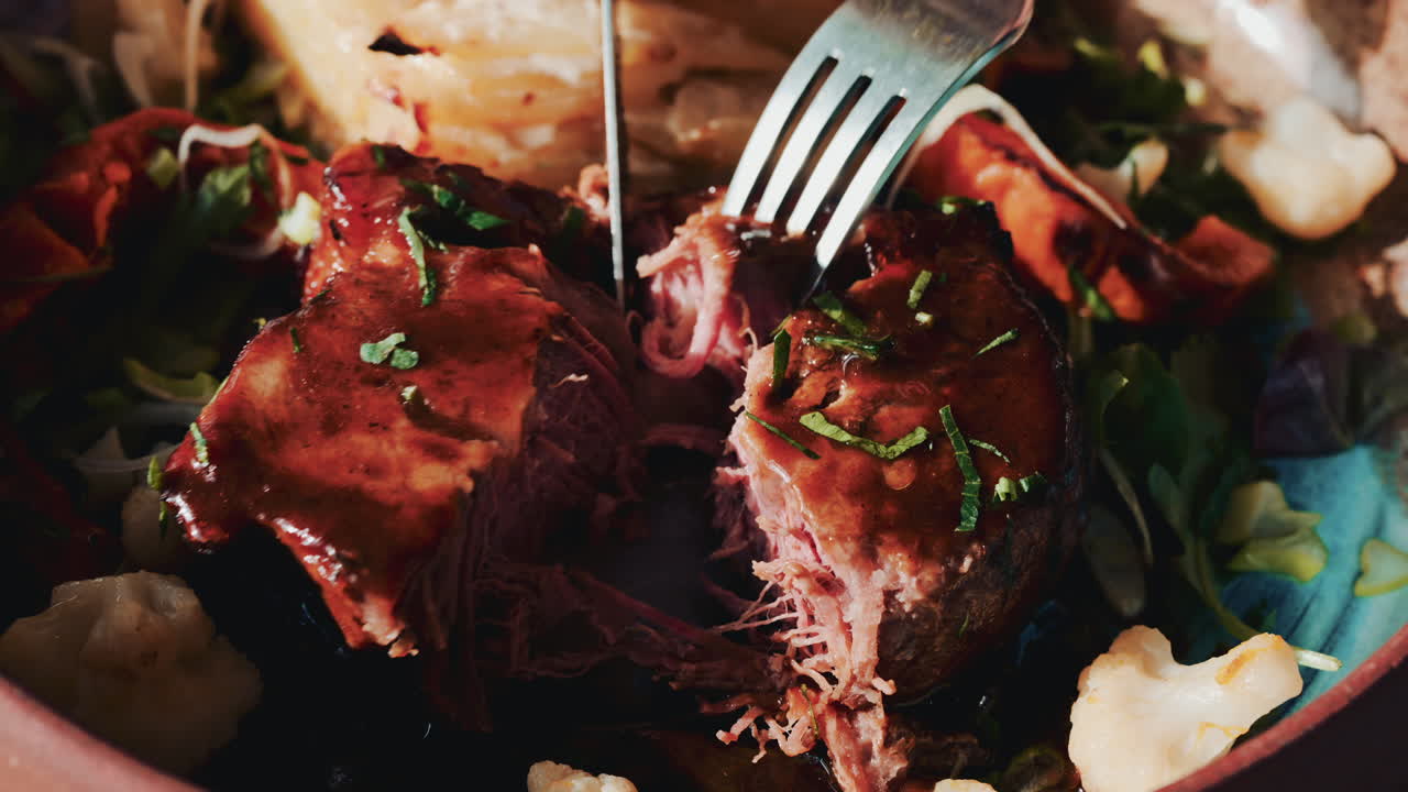 Close up of a fork and knife cutting into the tender meat, showcasing juiciness and texture
