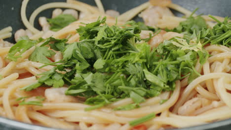 añadir perejil al plato de pasta con camarones