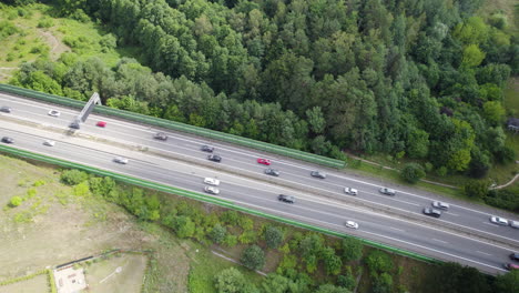 colpo aereo dall'alto verso il basso del traffico sull'autostrada circondata da campi e foreste a gdynia, in polonia