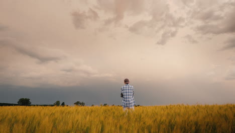 Un-Joven-Agricultor-Está-Solo-En-Un-Campo-De-Trigo-Contra-Un-Cielo-Tormentoso