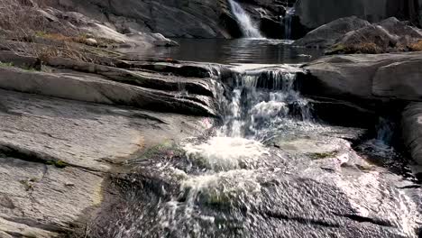 Langsamer-Drohnenflug-über-Wasser-In-Der-Nähe-Eines-Wasserfalls-Tagsüber