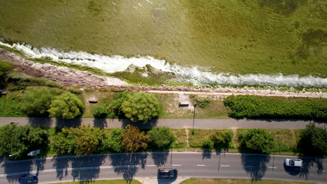 Vista-Aérea-De-Arriba-Hacia-Abajo---Carretera-Cerca-De-La-Costa---Automóviles-Circulando-Por-La-Carretera-Muy-Cerca-De-La-Costa---Agua-Espumosa-En-La-Orilla---Magnífico-Lugar-Turístico-Y-Escénico,-Kuźnica