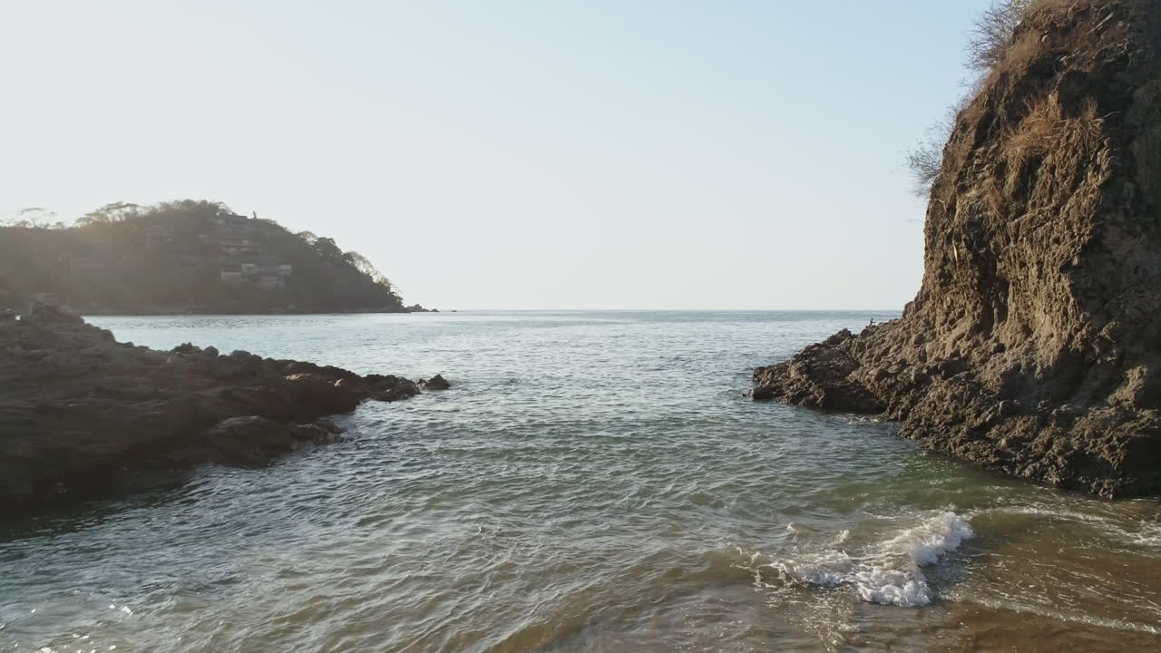 antena que pasa por encima mientras el hombre camina hacia las olas en una hermosa playa privada, 4k