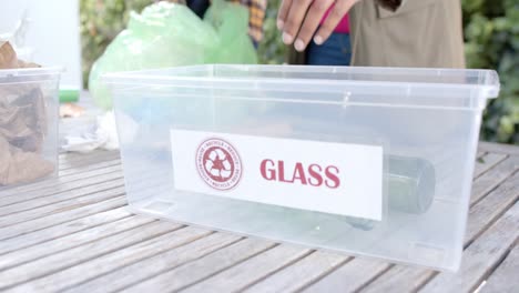 hands of african american couple collecting recycling in sunny garden, slow motion